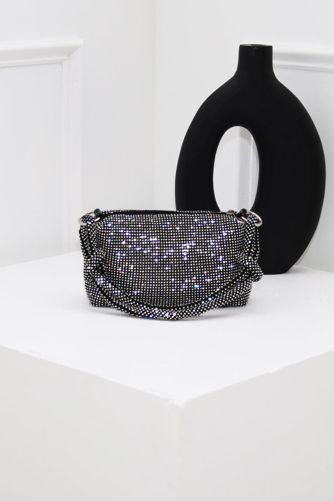 EDGE — black rhinestone-embellished top handle evening bag styled on a pedestal