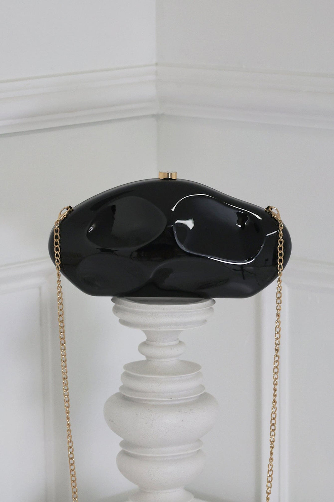 EDGE — black mirror-plated mini clutch displayed on a pedestal, front view flat lay