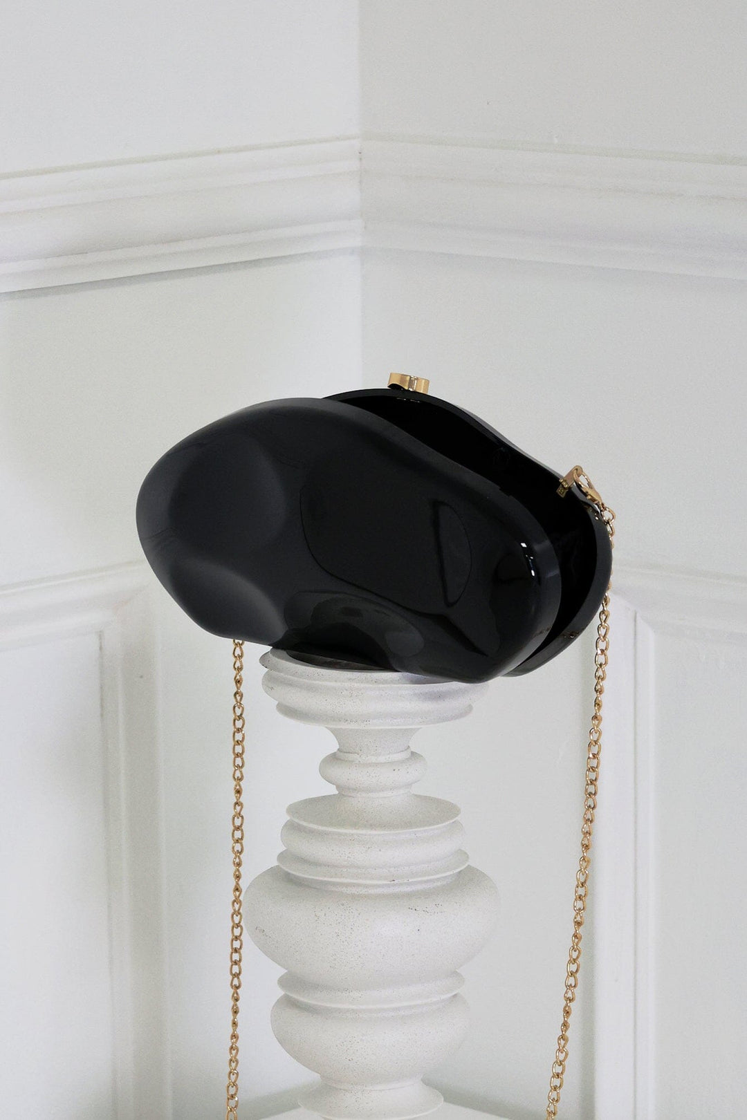 EDGE — black mirror-plated mini clutch displayed on a pedestal, side angle flat lay