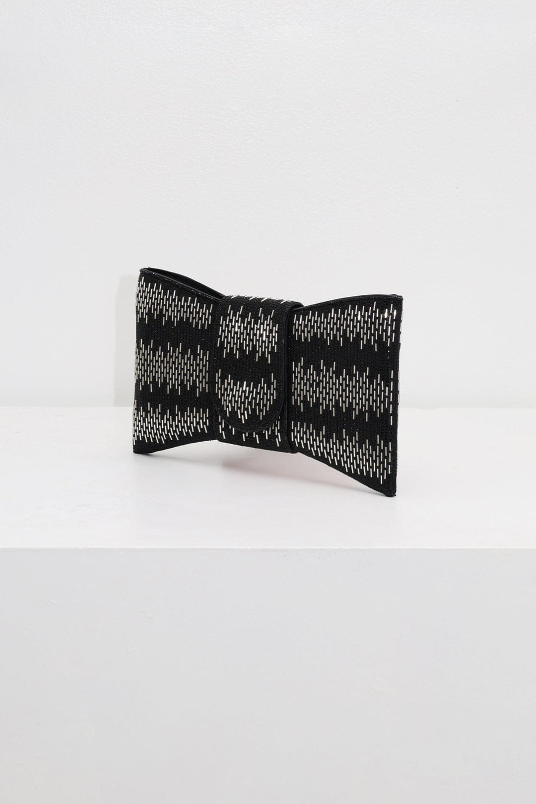 EDGE — black rhinestone bow-shaped evening clutch, angled view flat lay