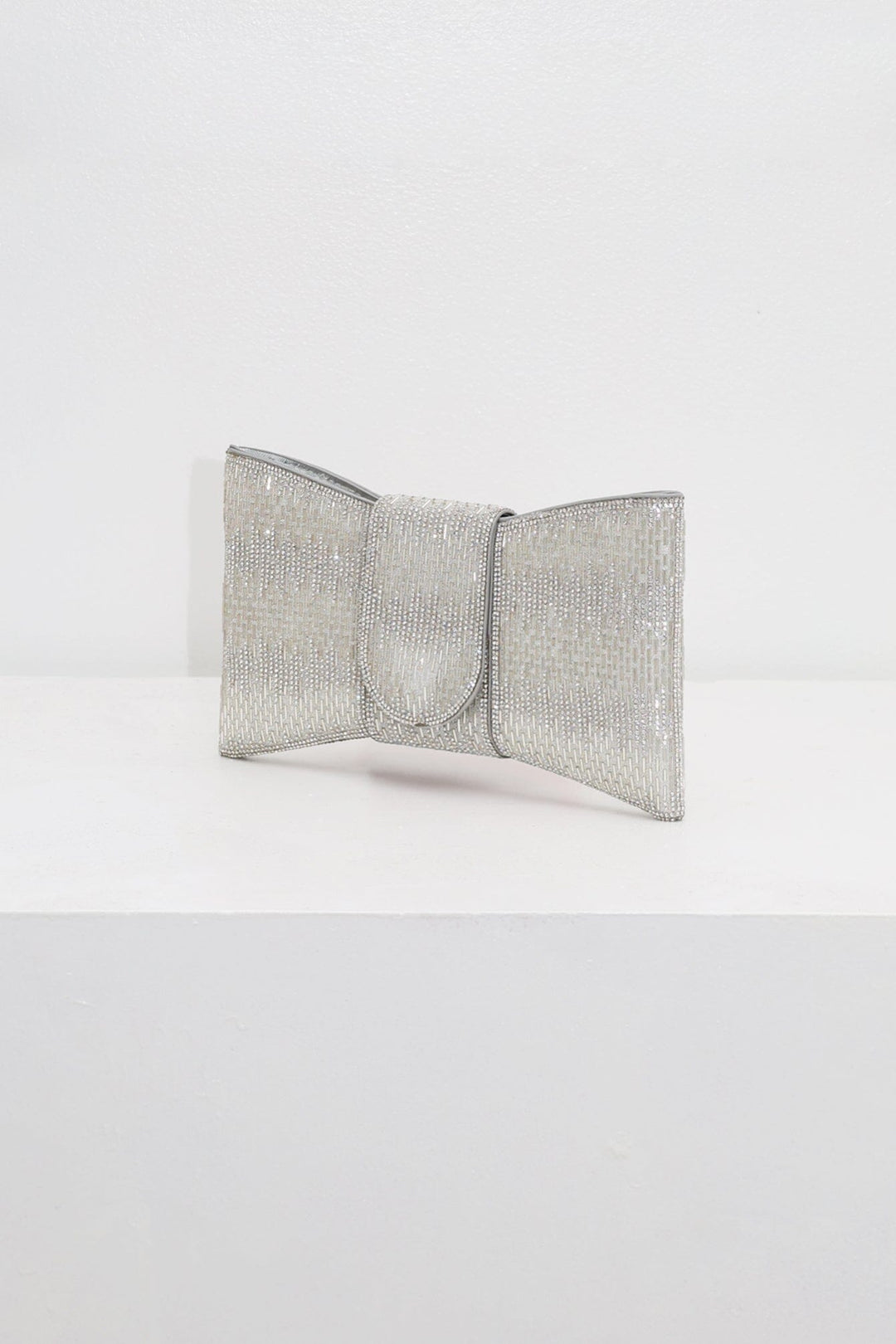 EDGE — silver rhinestone bow-shaped evening clutch, angled view flat lay