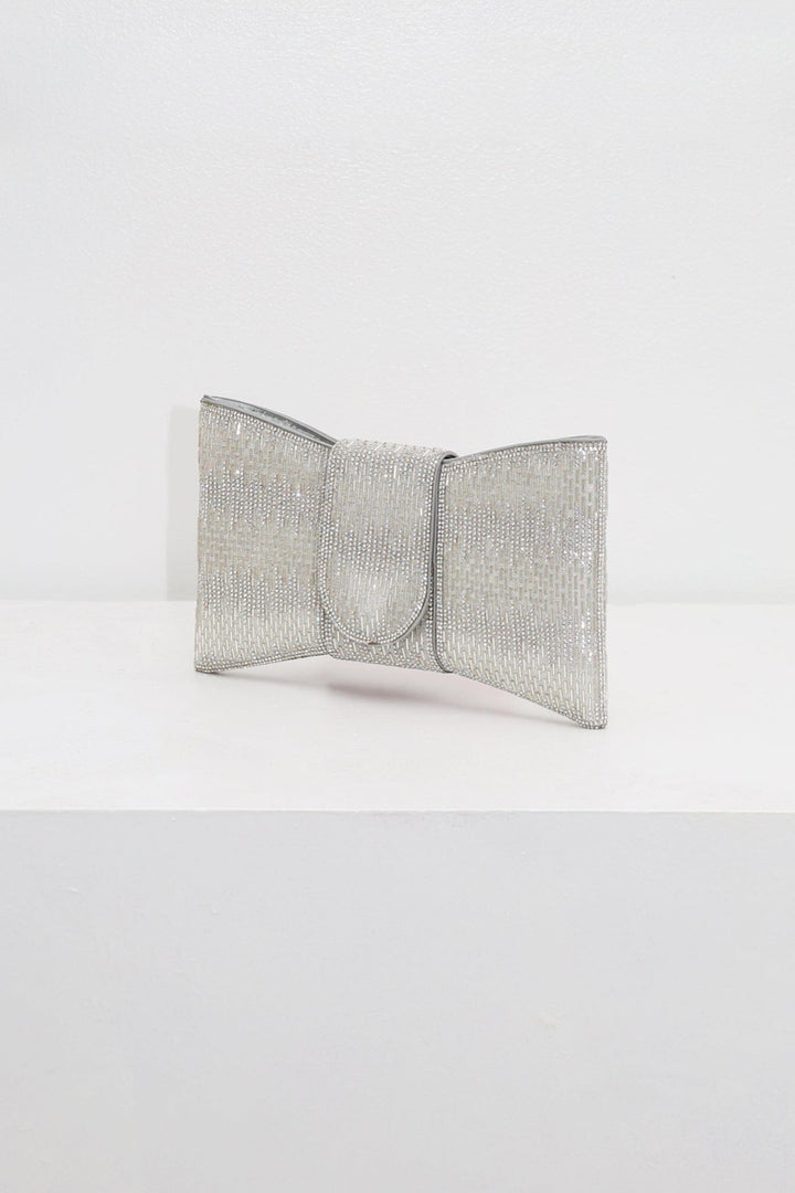 EDGE — silver rhinestone bow-shaped evening clutch, angled view flat lay