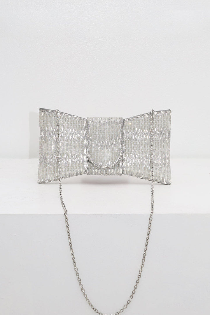 EDGE — silver rhinestone bow-shaped evening clutch with chain strap, flat lay