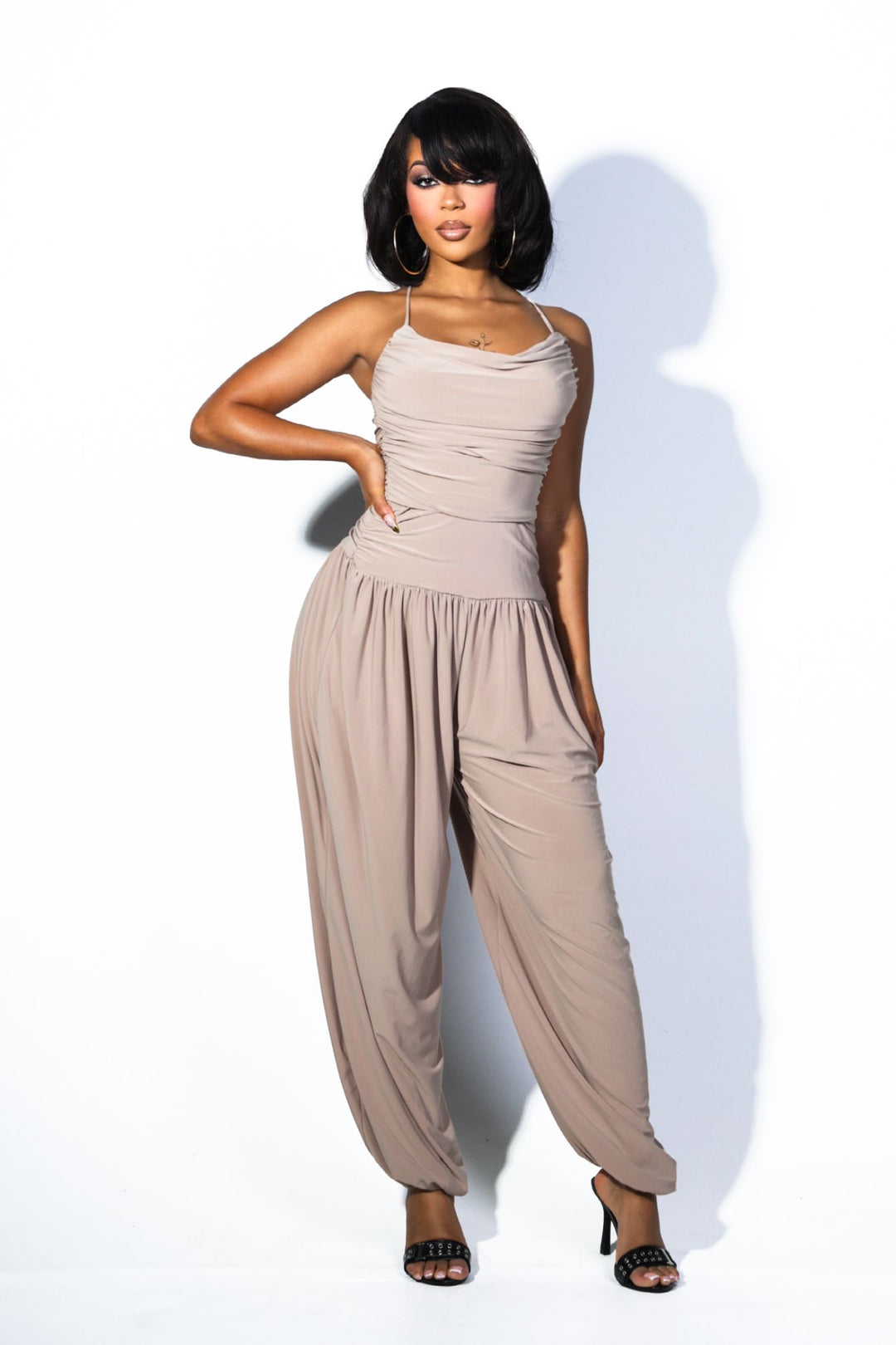 Tank top jumpsuit featuring draped cowl neckline with adjustable straps, Subtle horizontal ruched gathering across, Heavy gathering pants that taper at the bottom with elasticized ankle cuffs