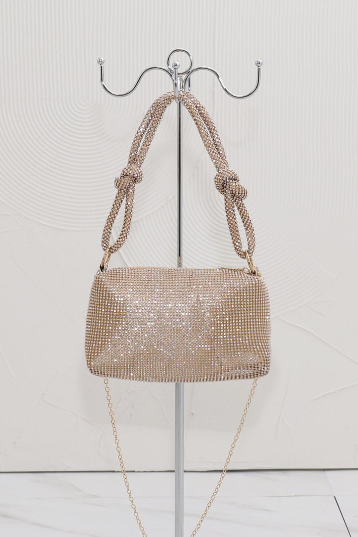 EDGE — gold rhinestone-embellished top handle evening bag displayed on a stand