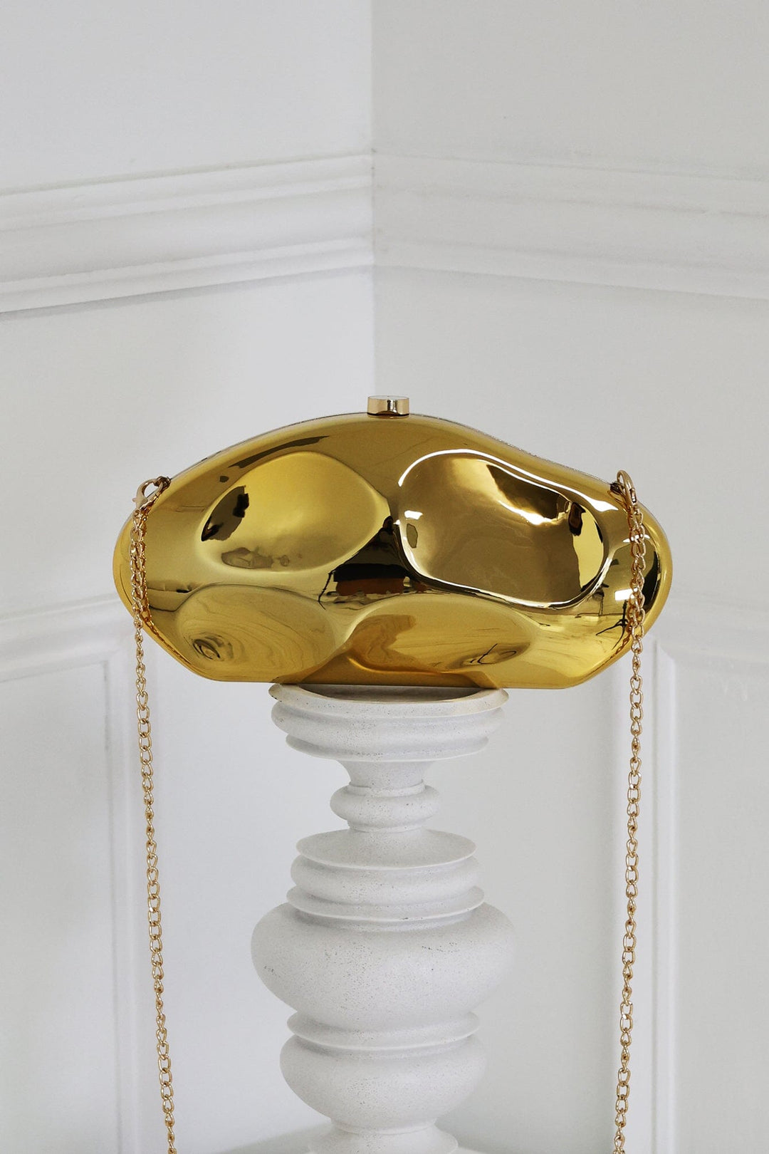 EDGE — gold mirror-plated mini clutch displayed on a pedestal, front view flat lay