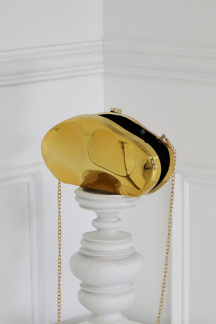 EDGE — gold mirror-plated mini clutch displayed on a stand, angled flat lay