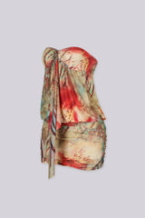 Abstract print tube mini dress featuring draped front detail with a metal accent and subtle volume through the waist
