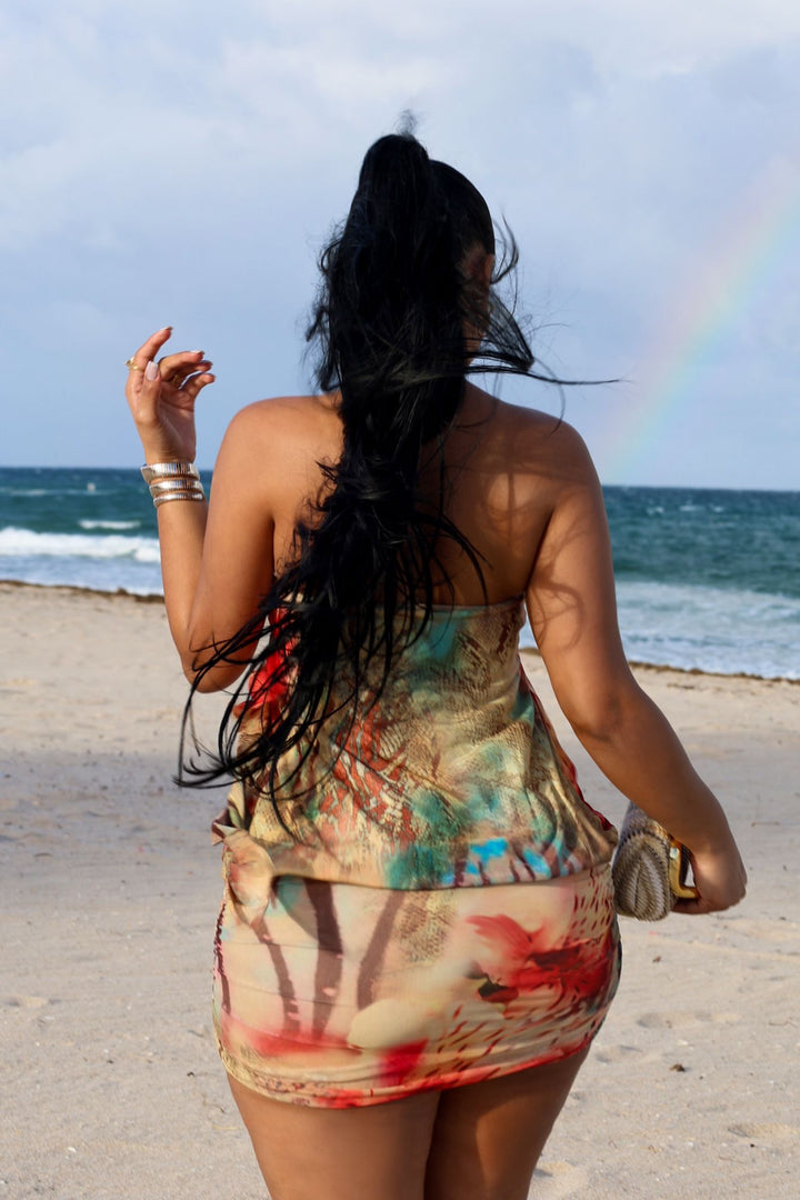 Abstract print tube mini dress featuring draped front detail with a metal accent and subtle volume through the waist