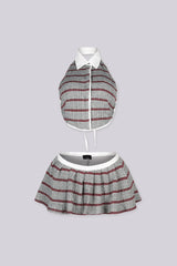 Cropped collared halter top with button front closure Matching low rise pleated mini skirt with contrast waistband