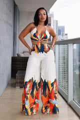 Halter neck jumpsuit featuring center O-ring with waist cut-outs, Edge gold chain straps connecting the front ring to the back ties