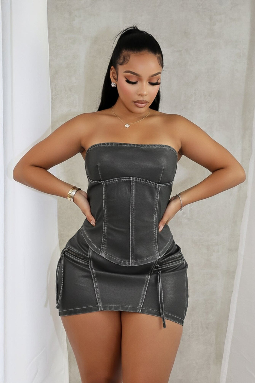 Faux leather low rise micro skirt with zip and tassel accenting on the sides featuring elasticized paneling at back