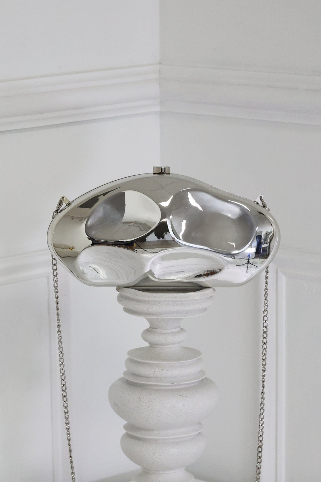 EDGE — silver mirror-plated mini clutch displayed on a pedestal, front view flat lay