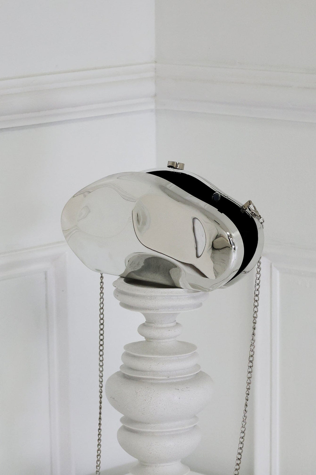 EDGE — silver mirror-plated mini clutch displayed on a stand, angled flat lay