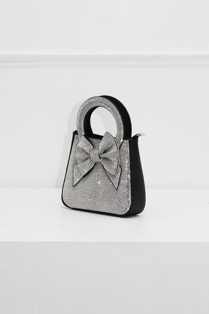 EDGE — black rhinestone bow-embellished top-handle mini clutch, side view flat lay