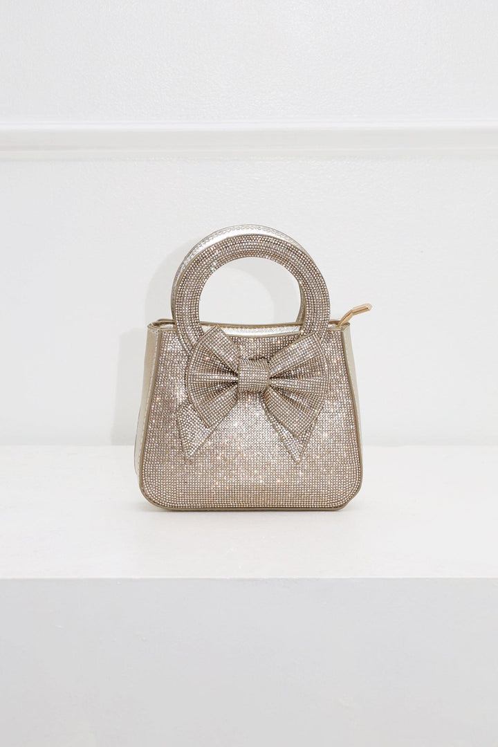EDGE — gold rhinestone bow-embellished top-handle mini clutch, front view flat lay