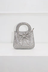 EDGE — silver rhinestone bow-embellished top-handle mini clutch, front view flat lay