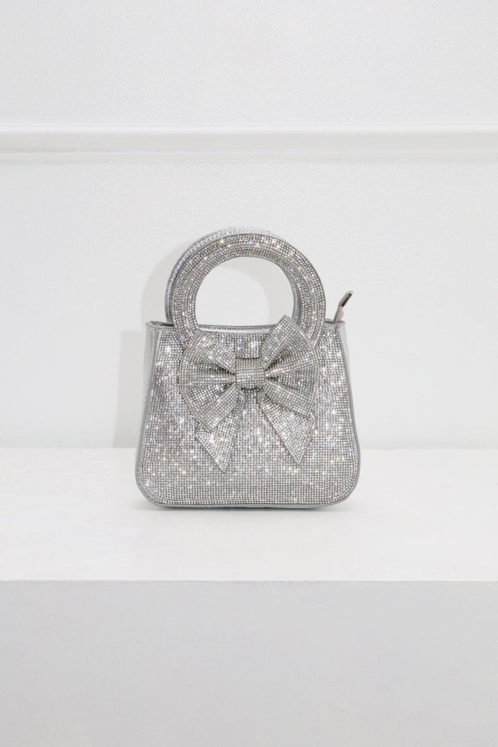 EDGE — silver rhinestone bow-embellished top-handle mini clutch, front view flat lay