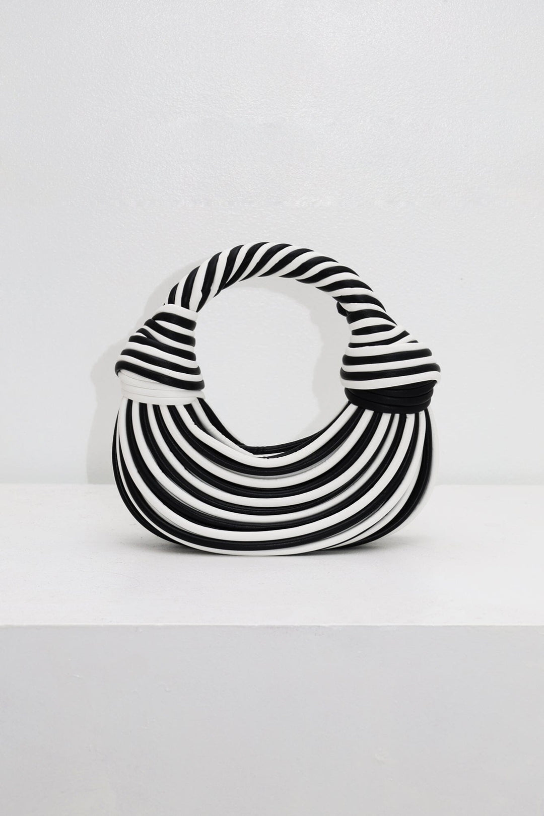EDGE — black and white striped half-moon top-handle bag, front view flat lay