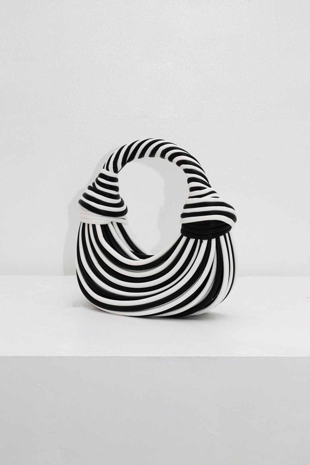 EDGE — black and white striped half-moon top-handle bag, alternate angle flat lay