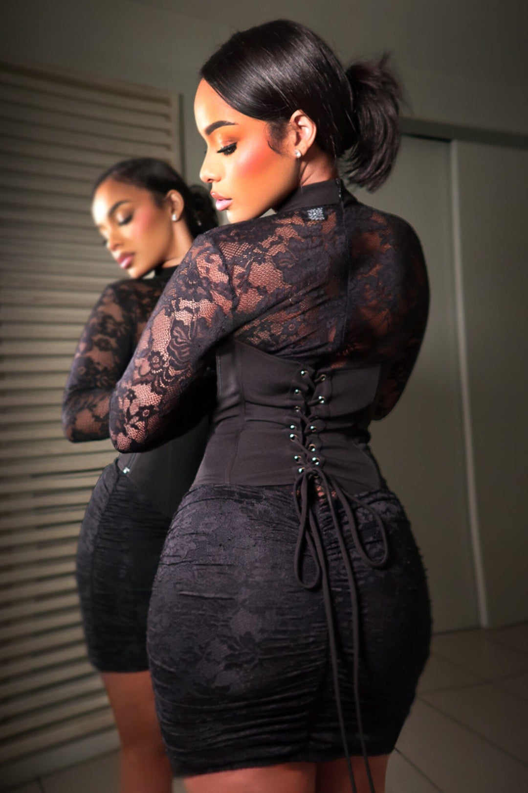 black lace long sleeve mini dress with a corset style back dress features sheer floral lace sleeves and a ruched laced up back detail