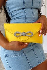 EDGE — yellow satin clutch with a crystal bow clasp, close-up held by a model